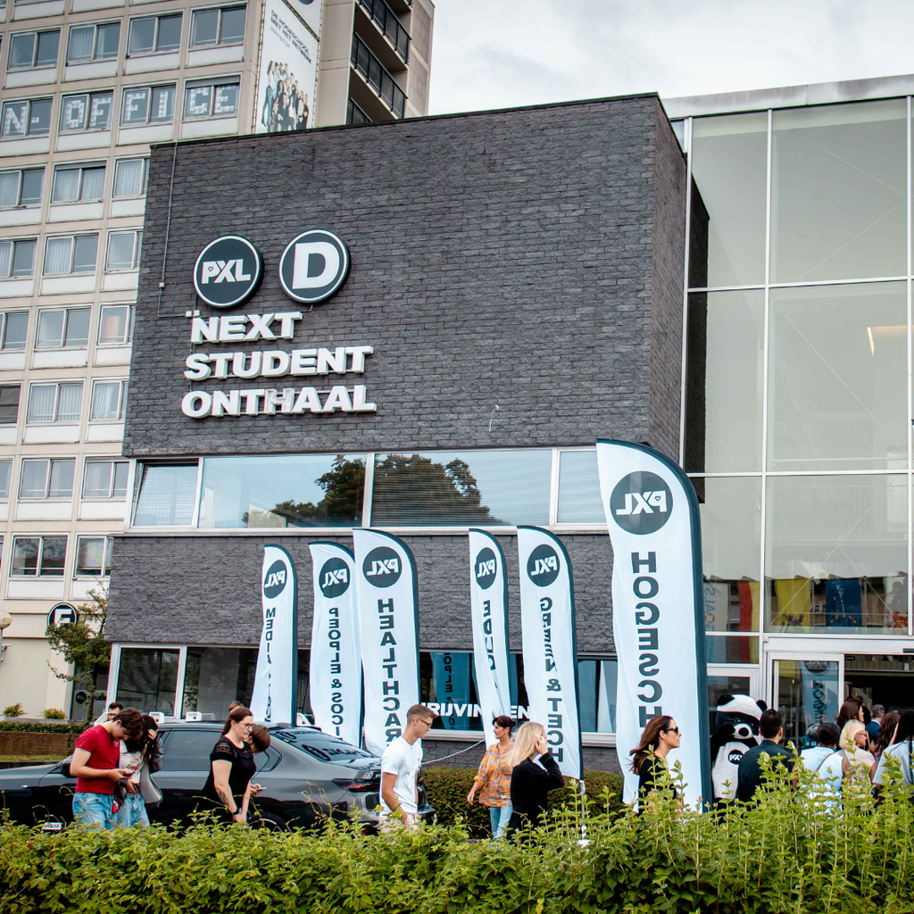 Studenten bij gebouw met blauwe vlaggen, zonnige dag.