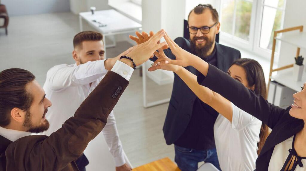 Groep collega's in kantoor, geven elkaar een high-five.