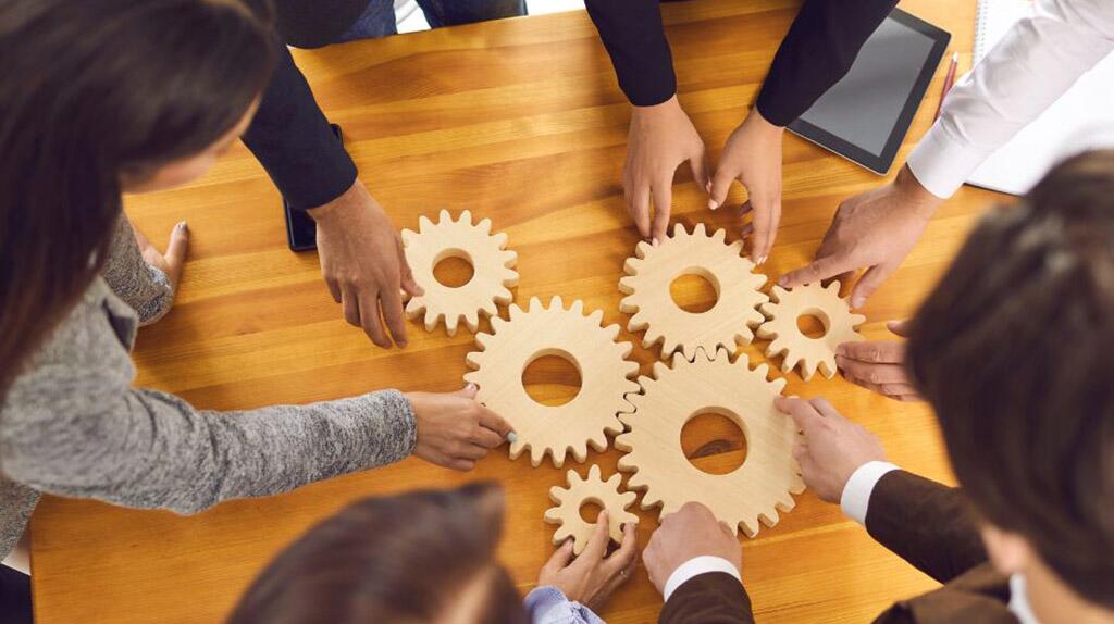 Mensenhanden plaatsen houten tandwielen samen op tafel.