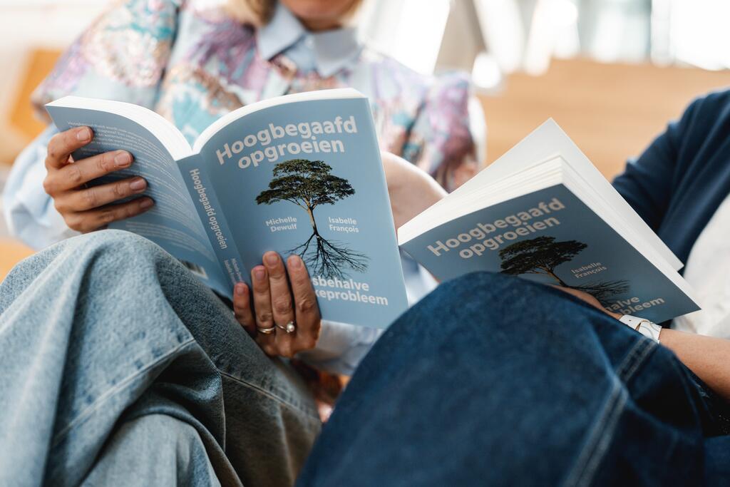 Twee personen lezen een boek met blauwe kaft en boomillustratie.