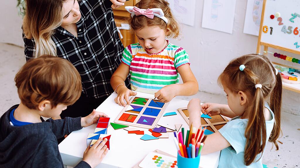 Kinderen knutselen aan een tafel met een volwassene erbij.