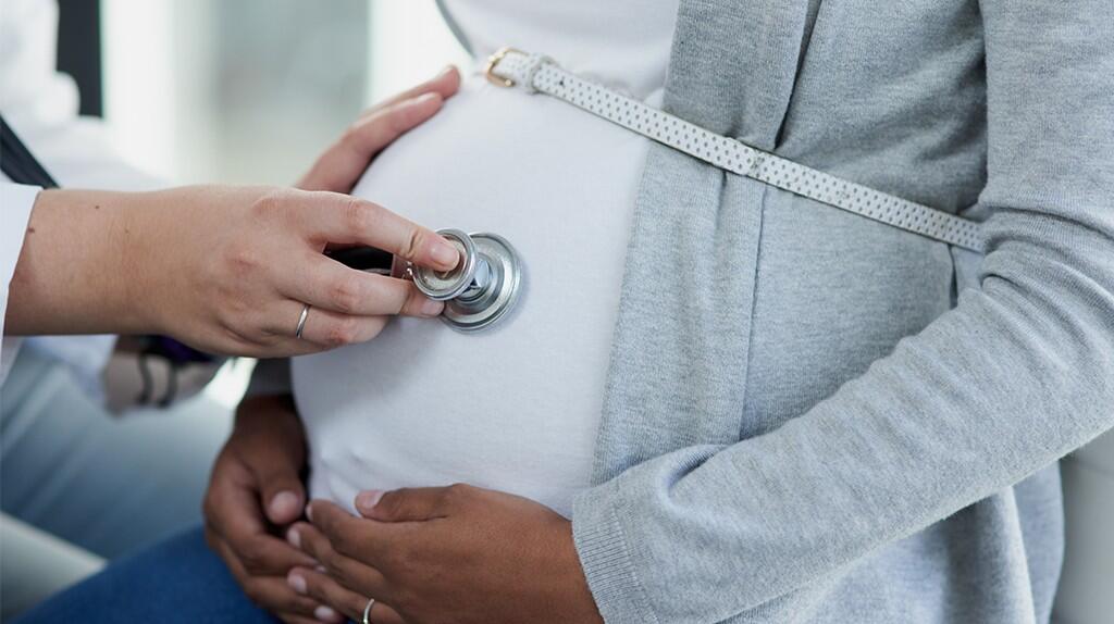 Arts controleert zwangere buik met stethoscoop.
