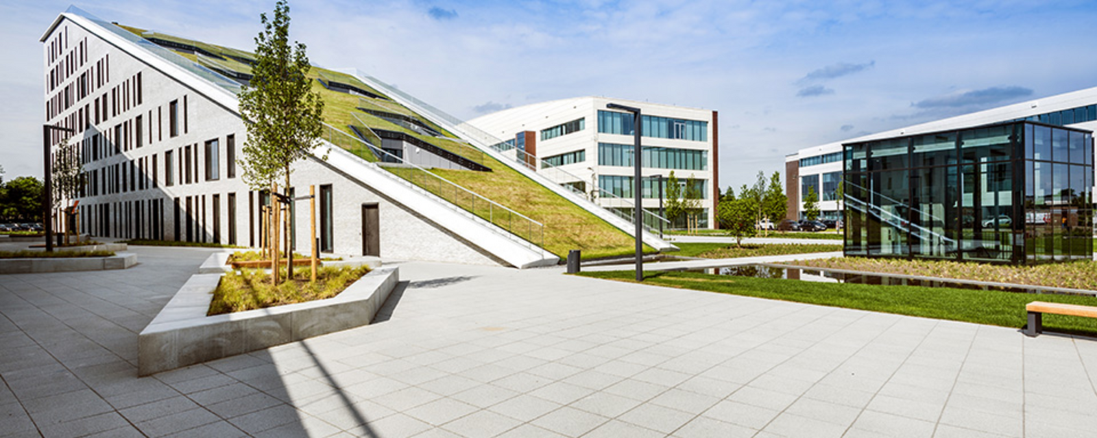 Moderne gebouwen met groene daken en glazen gevels onder blauwe lucht.