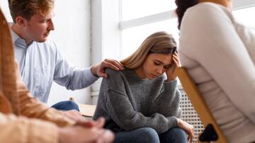Man troost verdrietige vrouw in een groep setting.