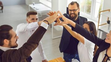 Groep collega's in kantoor, geven elkaar een high-five.