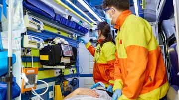 Paramedici behandelen patiënt in ambulance.