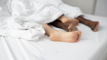 Voeten van twee mensen onder een witte deken.