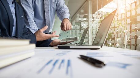 Twee mensen werken samen aan een laptop op kantoor.