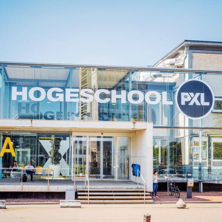 Hogeschool PXL gebouw met glazen gevel en blauwe lucht.