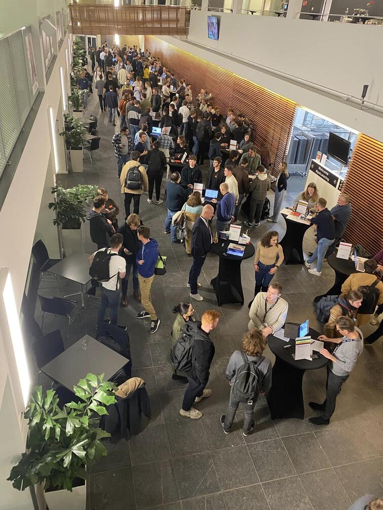 Grote groep mensen in een drukke hal tijdens een netwerkbijeenkomst.