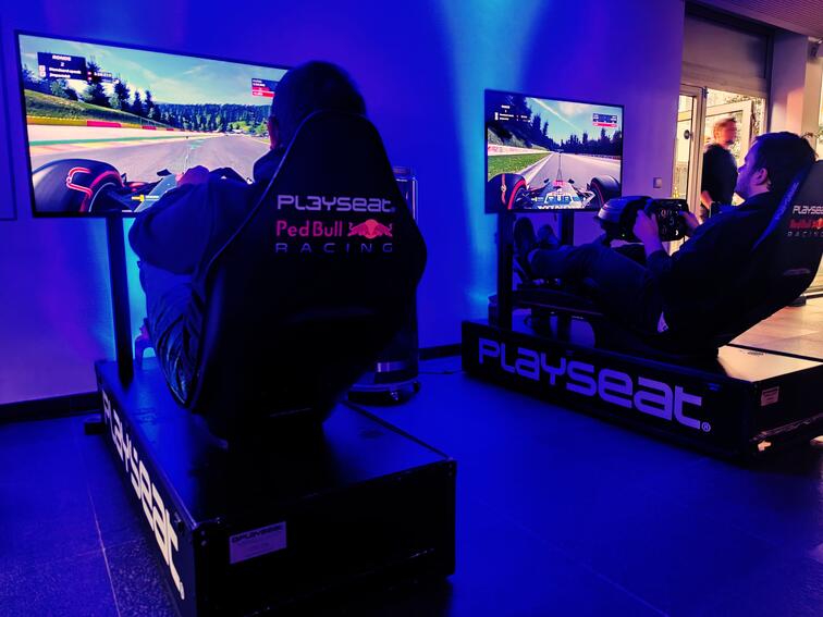 Twee personen racen in simulators met blauwe verlichting.