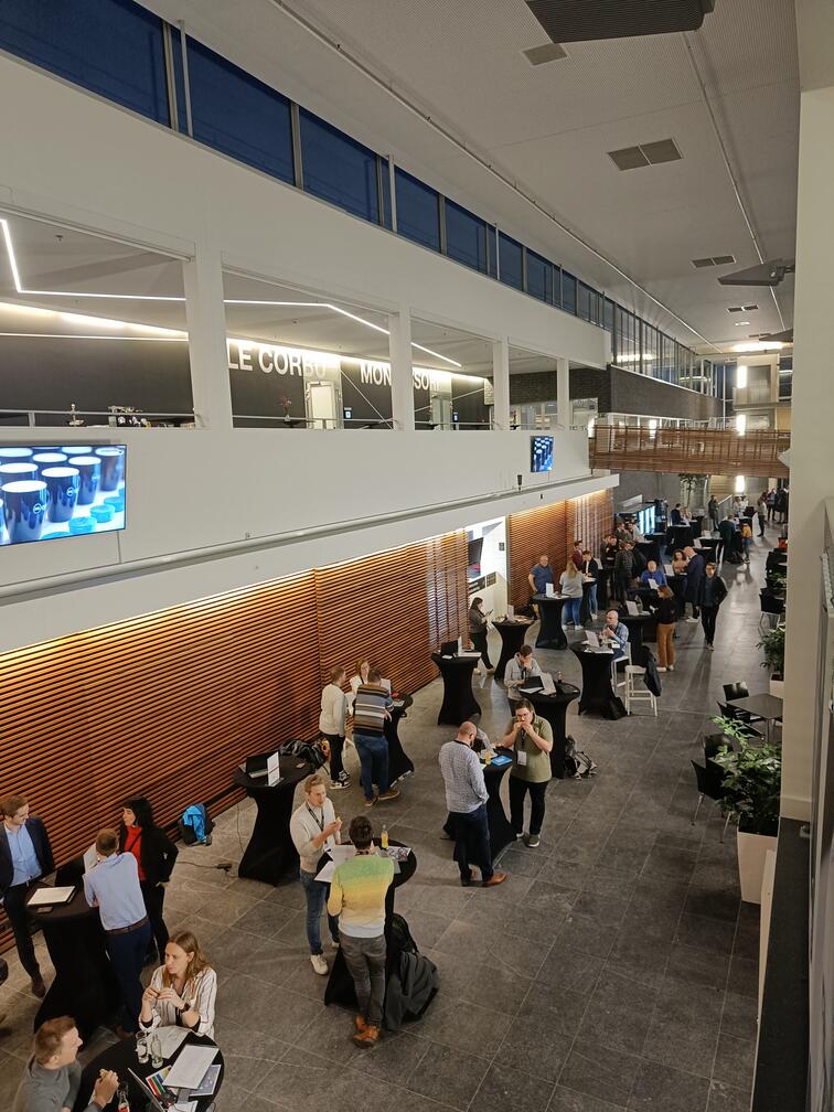 Zakelijke bijeenkomst in een moderne hal met tafels en mensen in gesprek.