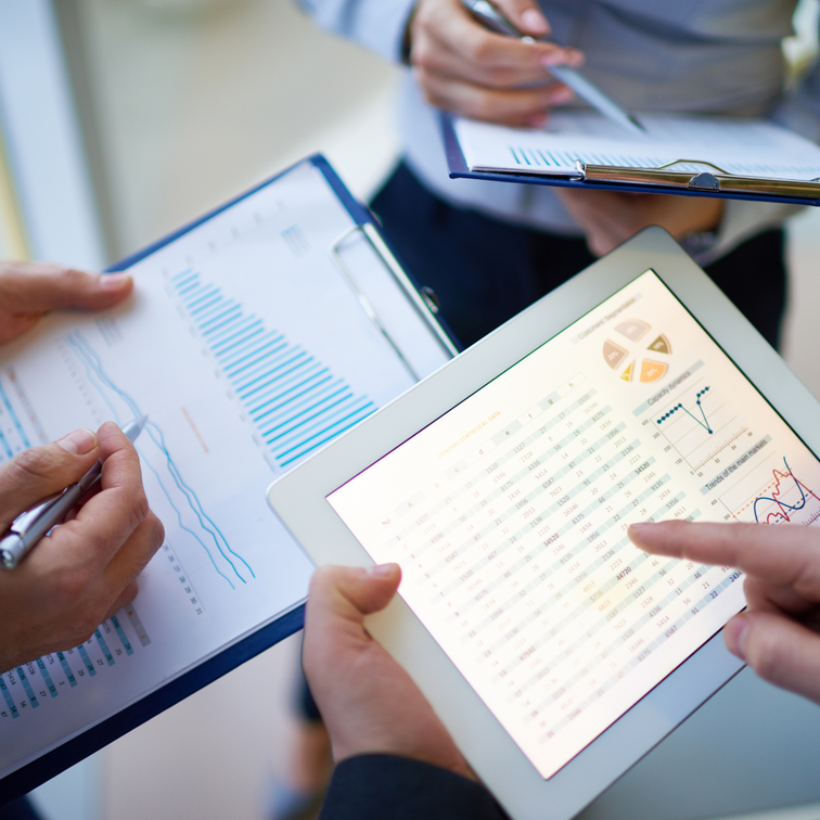 Tablet en documenten met grafieken worden besproken door mensen.