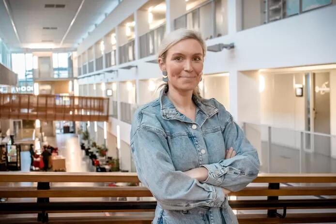 Vrouw in spijkerjasje poseert, moderne kantooromgeving.