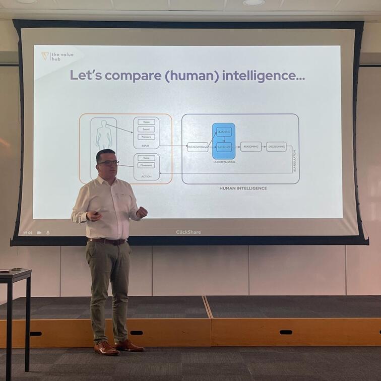 Man presenteert voor groot scherm met schema en tekst over intelligentie.