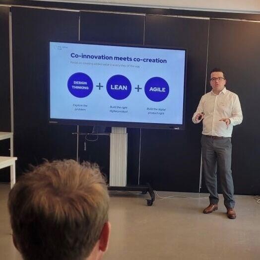 Man geeft presentatie met diagram op scherm in kantooromgeving.