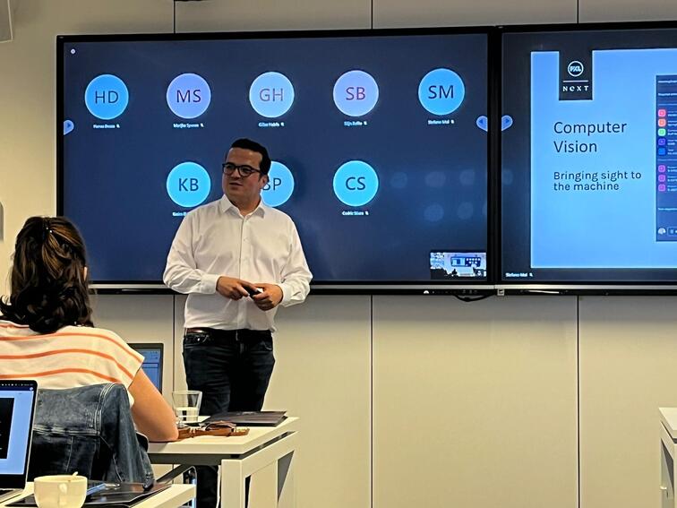 Man geeft presentatie in een klaslokaal, deelnemers kijken naar een groot scherm.