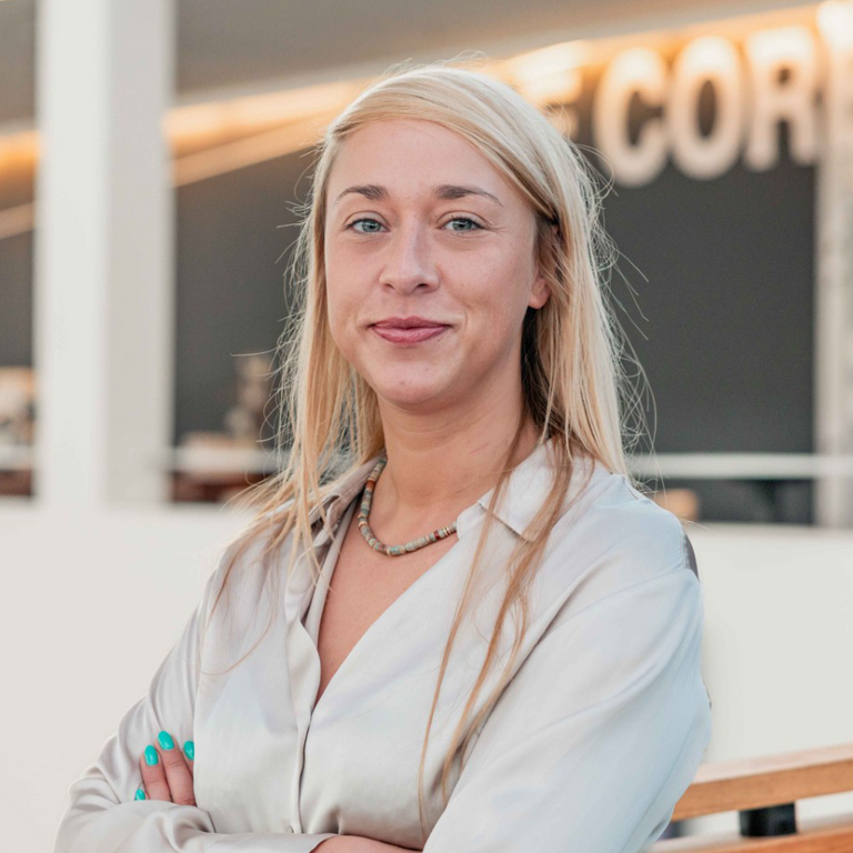 Vrouw glimlacht, staand in moderne kantooromgeving.